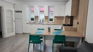 a kitchen with a wooden table and green chairs at Casa 2 Magurele in Măgurele