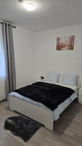 Un dormitorio con una cama grande con una manta negra. en Casa 2 Magurele, en Măgurele