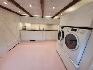 une cuisine blanche avec lave-linge dans l'établissement Villa Fuga kælderlejlighed, à Jelling