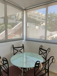 a glass table and chairs in a room with windows at Carvajal casa Tucan in Fuengirola
