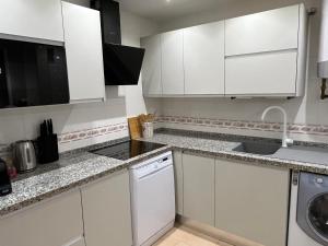 a white kitchen with white cabinets and a sink at Carvajal casa Tucan in Fuengirola +9 photos