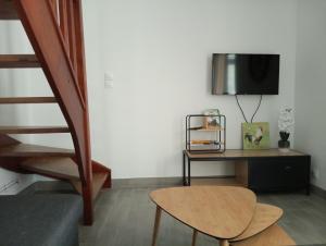a living room with a table and a tv at la parenthèse in Sainte-Mère-Église
