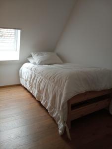 a bed in a white room with a window at la parenthèse in Sainte-Mère-Église