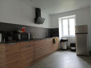 a kitchen with wooden cabinets and a stainless steel refrigerator at la parenthèse in Sainte-Mère-Église