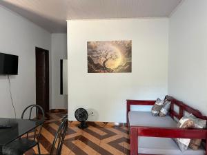 a living room with a table and a painting on the wall at Sol do Jalapão Kitnets Completas com Ar a 6km do Aeroporto de Palmas in Palmas