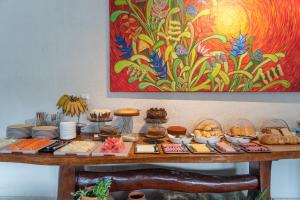 a table with food on it with a painting at Graciosa Suites in Praia do Frances +34 photos