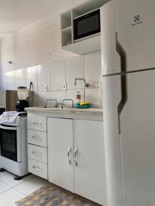 a kitchen with white cabinets and a refrigerator at Residencial Mais Viver São Francisco in Petrolina