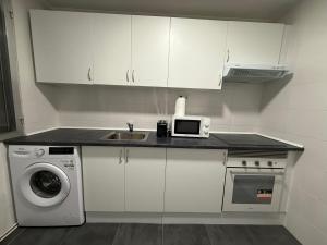 Una cocina blanca con fregadero y microondas. en Petithouse Madrid Camino Viejo, en Madrid