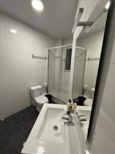 Un baño con lavabo, inodoro y espejo. en Petithouse Madrid Camino Viejo, en Madrid