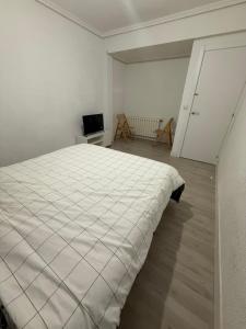 Un dormitorio blanco con una cama y un televisor. en Petithouse Madrid Camino Viejo, en Madrid
