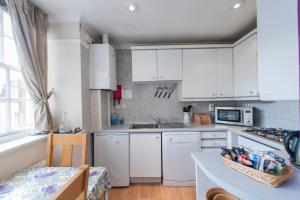 una cocina con armarios blancos y fregadero en Writers View, Royal Mile Apartment Edinburgh en Edimburgo
