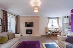 Writers View, Royal Mile Apartment Edinburgh في إدنبرة: غرفة معيشة مع أريكة ومدفأة