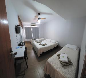 a hotel room with two beds and a television at Pousada Casagrande - São João in Volta Redonda