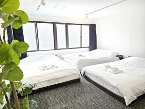 two beds in a room with windows at 2025年10月リニューアル! SLEEPLAB駒込-Komagome- in Tokyo