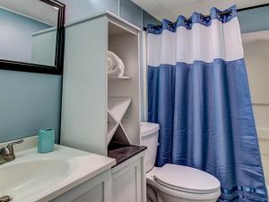 a bathroom with a toilet and a blue shower curtain at Tybee Tree House in Tybee Island +21 photos