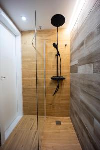a glass shower in a room with a wooden wall at Piraeus Harbor Hideaway in Piraeus