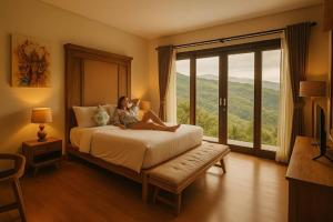 a woman sitting on a bed in a room with a window at Shitala Villa in Munduk