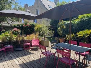 un patio avec une table, des chaises et un parasol dans l'établissement Maison de charme, jardin clos sud, terrasse, 2 minutes plages, au cœur du village de Piriac, 4 chambres 2 SDB., à Piriac-sur-Mer