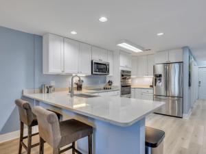 a kitchen with white cabinets and a large island with bar chairs at Relax-Unwind-Enjoy in Tybee Island