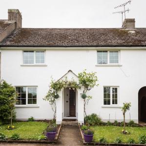 a white house with purple plants in front of it at Spacious 3 Bed Cottage Near Beaches in Georgeham
