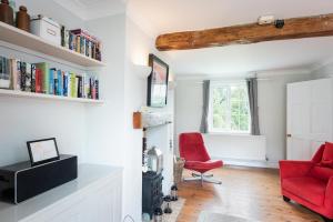a living room with a red chair and books at Spacious 3 Bed Cottage Near Beaches in Georgeham