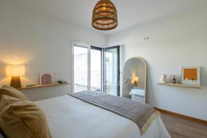 a white bedroom with a bed and a mirror at Valentin House by ACasaDasCasas in Santo Isidoro
