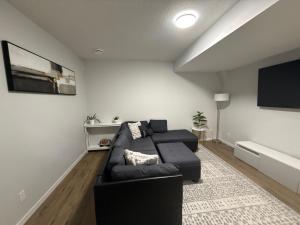 a living room with a black couch and a flat screen tv at The Seton Nook - 1BR Suite Near Seton Health Campus, Cineplex and YMCA in Calgary