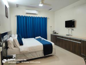 a bedroom with a bed and a blue curtain at Hotel Vilaari Blue Marina in Visakhapatnam