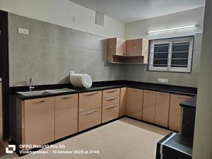 a kitchen with brown cabinets and a sink at Hotel Vilaari Blue Marina in Visakhapatnam