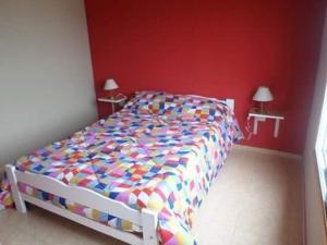 a bed in a bedroom with a red wall at Duplex Carlos in San Clemente del Tuyu