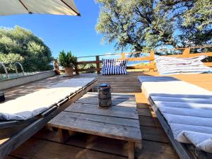 a wooden deck with two beds and a table at Maison de maître en pierre de 1831 avec vue sur la mer à Porticcio in Porticcio