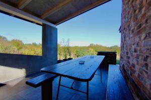 een houten tafel op een patio met een bakstenen muur bij Kuća za odmor MIRINA in Aljmaš