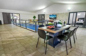 a dining room with a table and chairs and a pool at וילה סאן טורינו - Vila San Torino in Elqosh