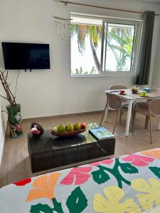 a living room with a table with a bowl of fruit at Bord de Mer, Coco Fare Beach, Tahiti in Punaauia