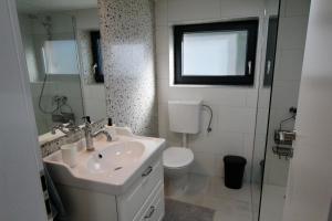 een badkamer met een wastafel en een toilet en een raam bij Kuća za odmor MIRINA in Aljmaš +30 foto's