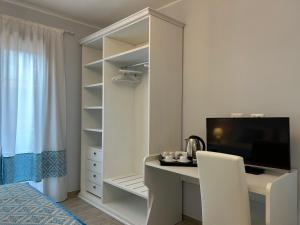 a white bedroom with a desk and a tv at Domu Jole B&B in Selargius