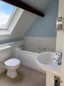 a bathroom with a toilet and a tub and a sink at Kissingstone Cottage - Hidden Gem! in Stroud +11 photos