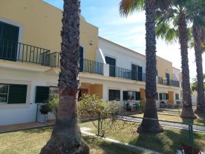 una hilera de palmeras frente a un edificio en Oasis Encosta, en Estibeira