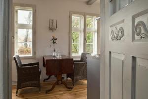 a dining room with a table and chairs and windows at Gärtnerhaus in Cuxhaven