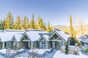 a house covered in snow with trees in the background at The Snowbird by Whiski Jack in Whistler