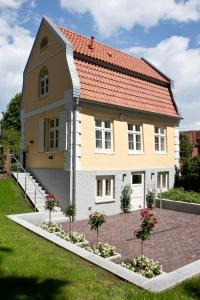 ein Haus mit rotem Dach auf einer Ziegelsteinfahrt in der Unterkunft Gärtnerhaus in Cuxhaven