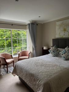 a bedroom with a bed and two chairs and a window at The Grove Lodge Guesthouse in Killorglin