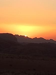 a sunset over the mountains in the desert at Wadi Rum Ali Camp &Tours in Wadi Rum