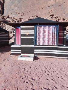 a house with colorful curtains sitting on the beach at Wadi Rum Ali Camp &Tours in Wadi Rum