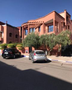 马拉喀什Chez l'artiste的两辆汽车停在一栋建筑前的停车场