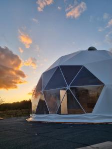 une tente sur un parking avec le coucher de soleil en arrière-plan dans l'établissement GlampingDenis Igloo, à Mihăeşti