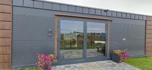 eine große Metallgarage mit Glastüren und lila Blumen in der Unterkunft DuoDomkyTa3 in Spišská Belá