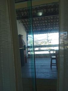 a glass door to a patio with a table and a chair at Varanda palmeiras in Cabo Frio