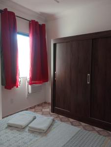 a bedroom with a door and two towels on a bed at Varanda palmeiras in Cabo Frio