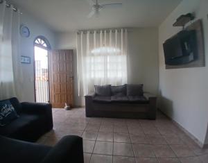 a living room with a couch and a tv at Nossa Casa com Piscina in Guarapari